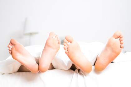 women's and men's feet sticking out from under the covers